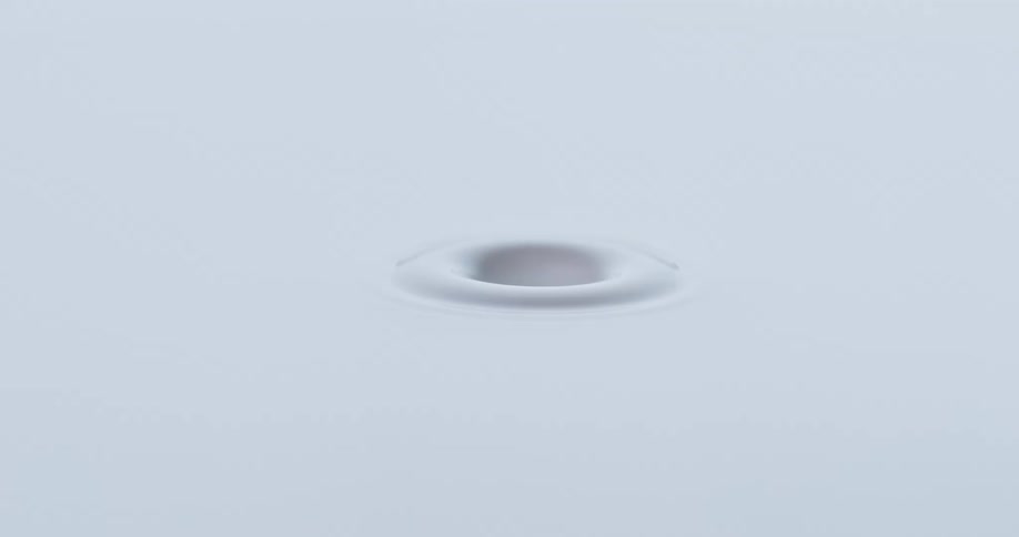 An orb falls into a white liquid and creates a circular ring and splashes back up