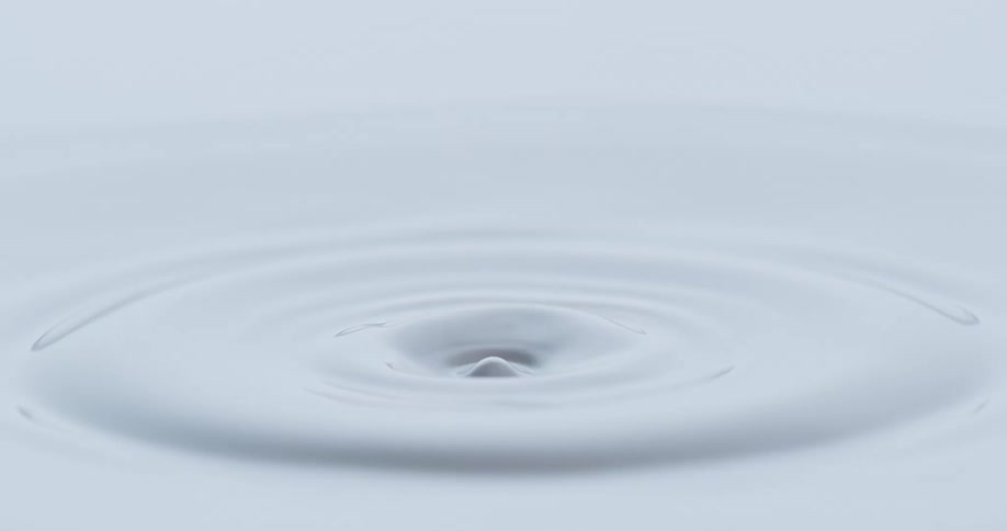 White paint being dropped into by a white droplet creating a splash and ripples on the surface