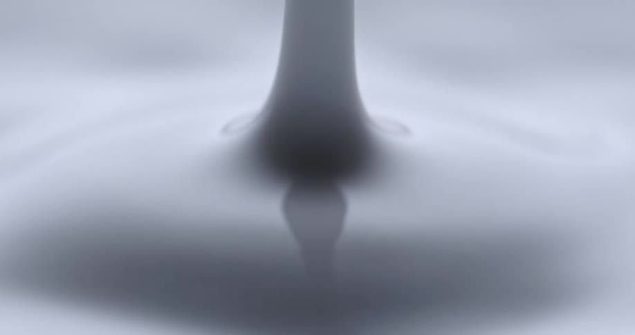 Larger drop falls creating splash and ripples in pale milky liquid