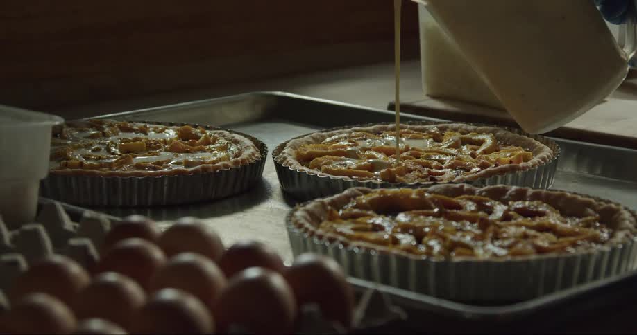A baker pours honey onto a peach tart