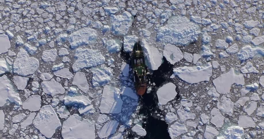 A large boat breaks through the icy water below