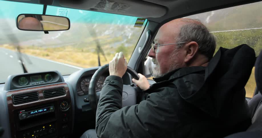 A man is driving and talking to someone next to him