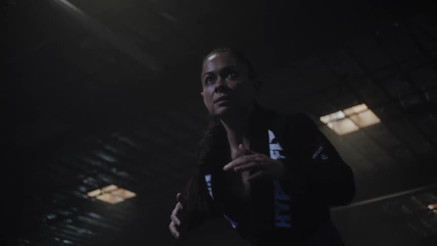 A woman moves into the shot and gets in a fighting stance