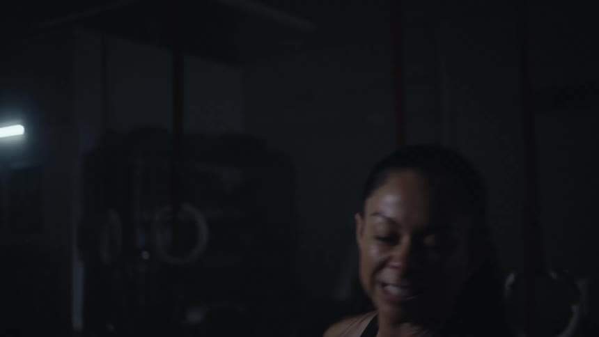 Sweaty woman with ponytail and sports bra swings in the gym