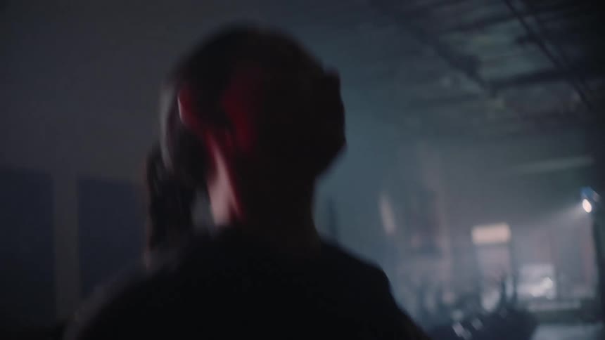A woman is standing in a smoke filled room jumping up and down and moving her arms