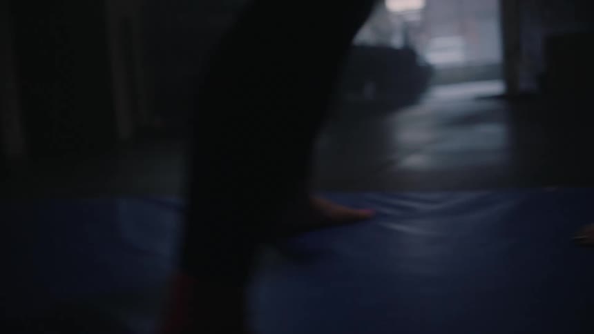Two people with bare feet are standing on a mat facing each other and taking a few steps