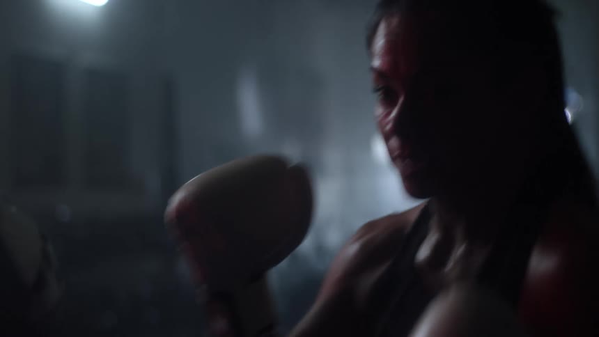 A woman wearing boxing gloves practices hitting pads held by another woman