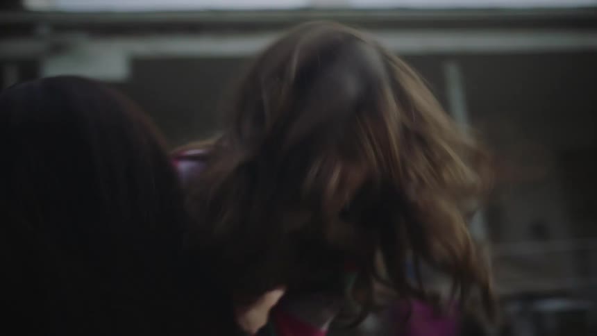 Playing mother runs forward to pick up daughter thencarries her back and forth on her shoulder in yard of house