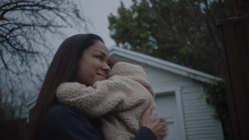 A woman carries her daughter during a walk in their neighborhood