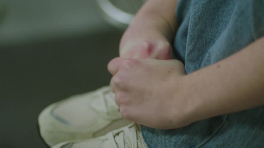 A close up of a girl sitting with headphones on with her arms wrapped around her knees