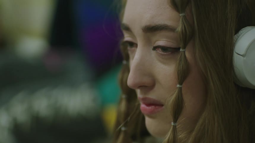 A close up of a womans face as she looks sad distraught and angry before taking off her headphones