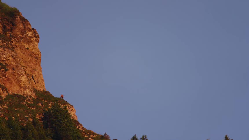 Someone does gymnastics moves on a cliff side in the horizon