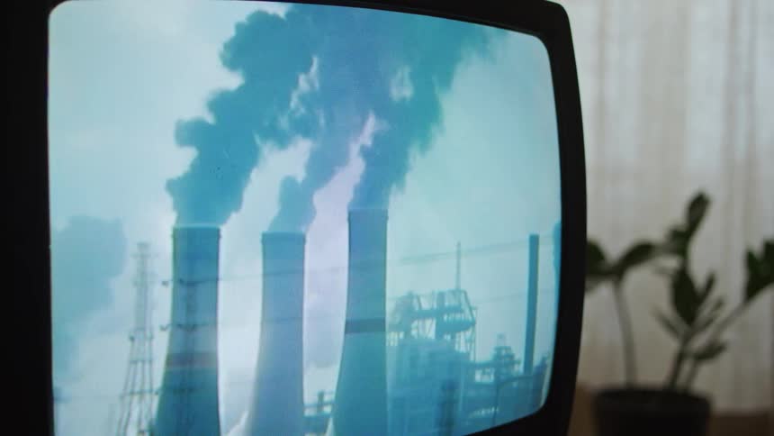 Pollution from factory smoke stacks is on a television screen