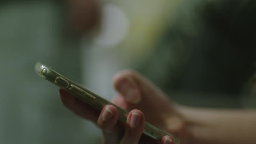 A shaking hand scrolls and taps on a smartphone