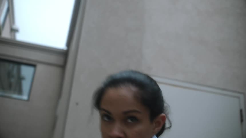 A woman housekeeper throwing air punches in a back alley