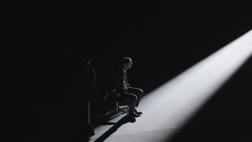 A man sitting in an empty room stands up
