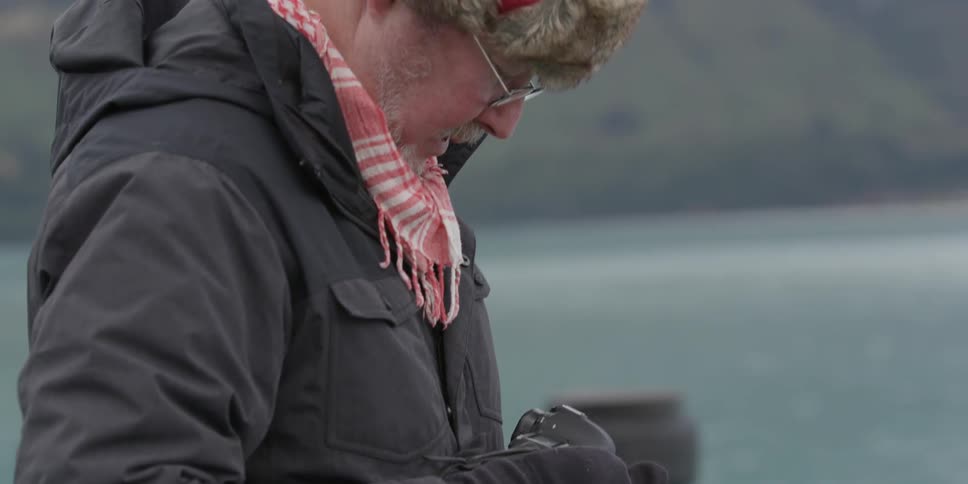 A man near the water looks into his camera