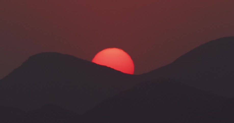 The sun is setting behind the mountain