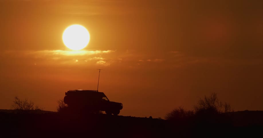 Desert-adapted lion research vehicle is parked in a field at dusk