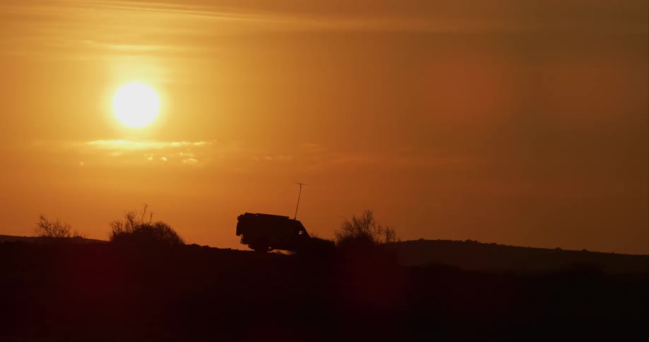Desert-adapted lion research vehicle drives off road as the sun sets