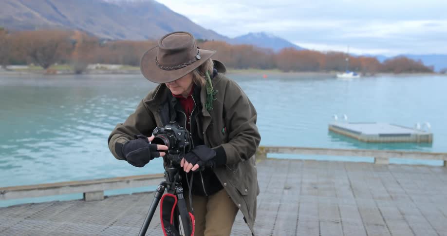 Two people are adjusting their cameras on tripods