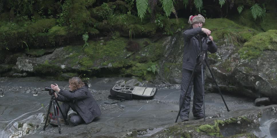 A man and woman adjust their cameras
