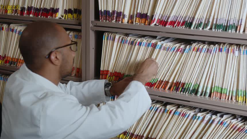 A doctor is getting a file for someone inside of a clinic