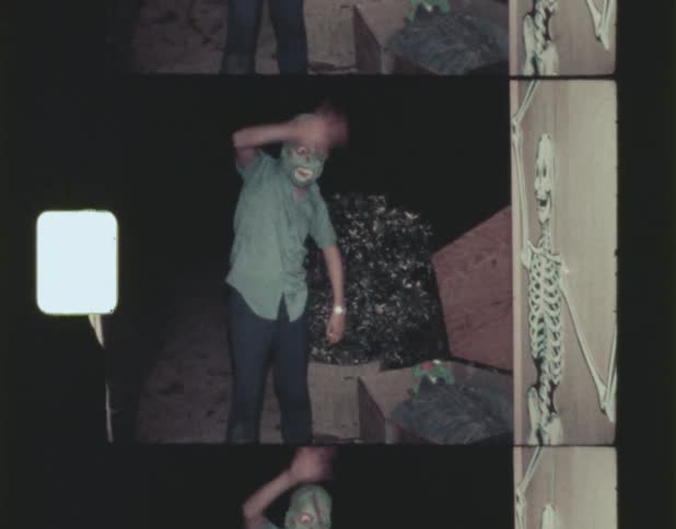 A man wearing a peculiar or unusual mask is waving to the camera