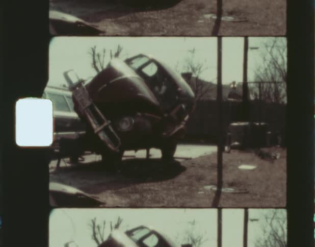 A man pushes and tilts the outer body of a car onto its side