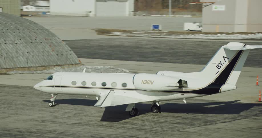 A small white airplane parked at an airport field next to a half dome