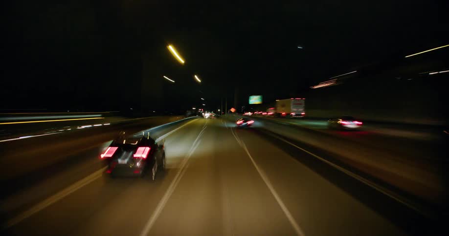 A time lapse of traffic driving through a tunnel and driving near a city on the other side