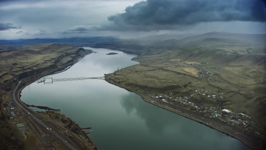 An aerial of a waterway separating hills buildings and a highway