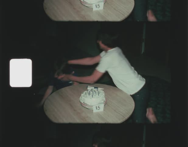 A teenager jokingly chokes his brother after blowing out candles on his birthday cake