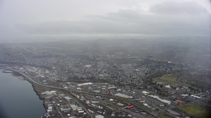 Light traffic moves along highway passing through foggy city close to the river in parts