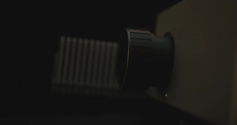 A white projector box displaying an image from the lens as film enters into it
