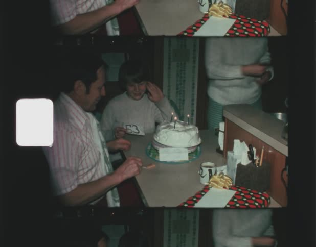 A man hides a piece of paper showing his age before blowing out birthday candles