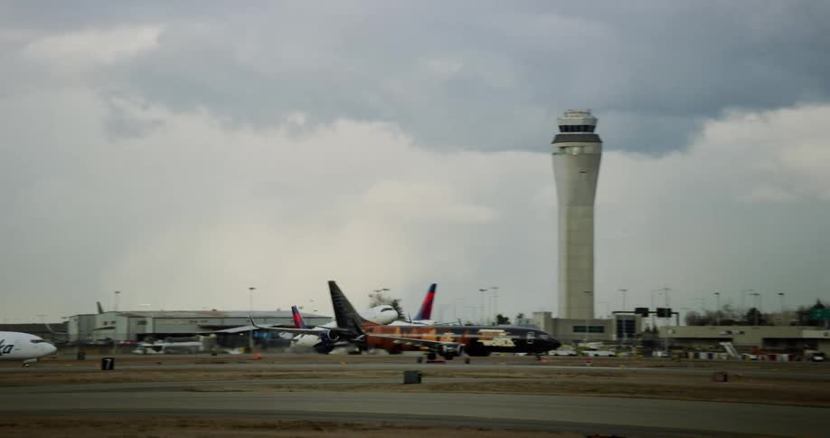 Airplanes move along landing strips at airfield and one plane takes off