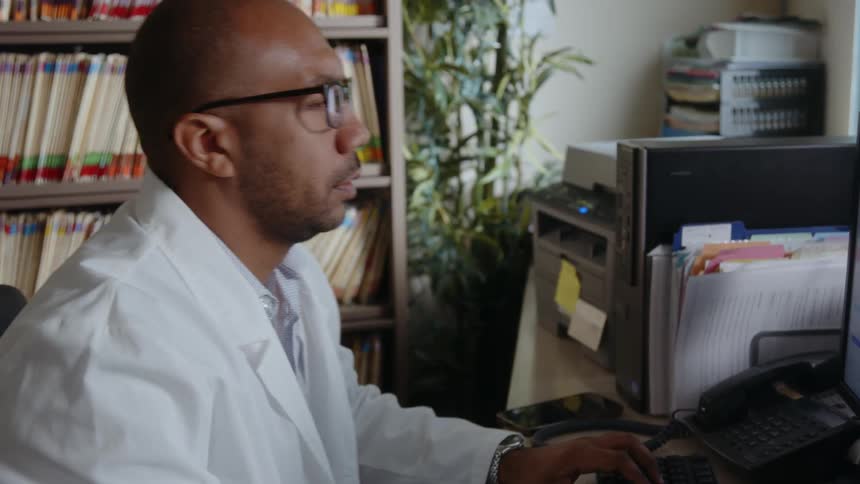 A man is typing on his computer in his office