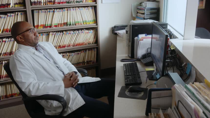 In his office a man pauses his typing his face filled with fear and confusion as he stares intently at the computer screen surrounded by numerous books on the shelves behind him