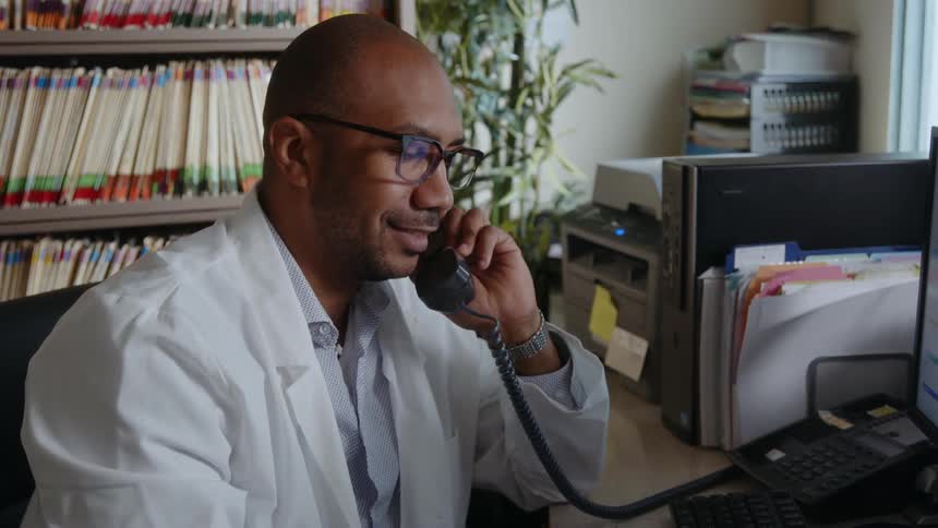 A man is working in his office and talking on a phone