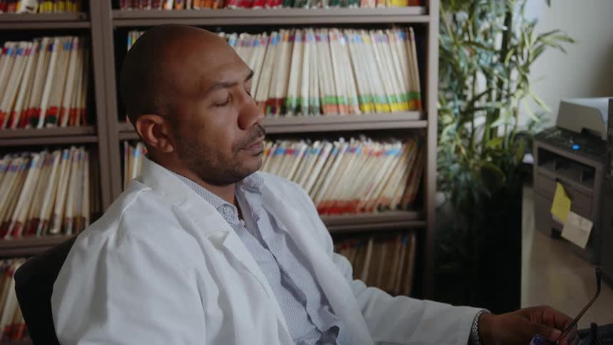 A man is sitting at his computer desk in his office