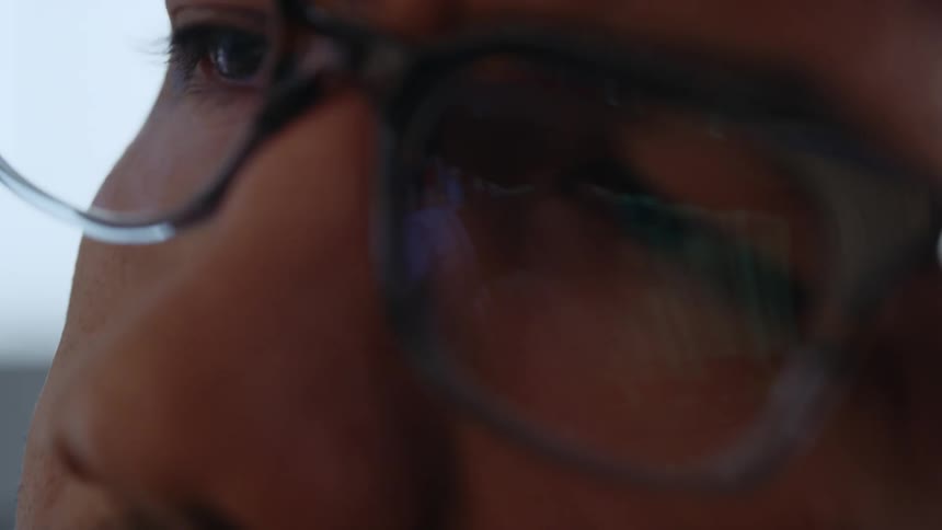A person with glasses speaks sadly