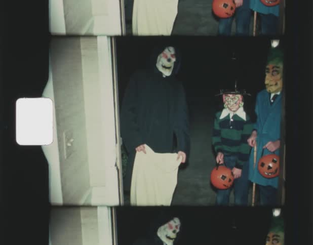 Three boys stand in their halloween costumes at the front door of a home