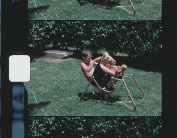 Boy thats too old playing on a spring rocking horse in the yard