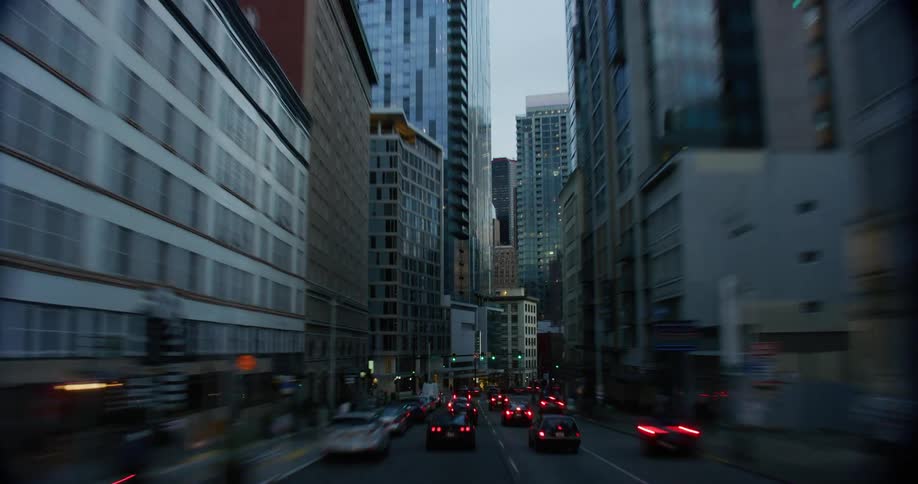 Cars are driving through a downtown city at midday