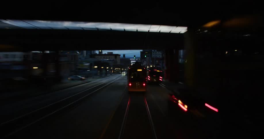 Time lapse of a yellow cable car driving on a road in the city at evening