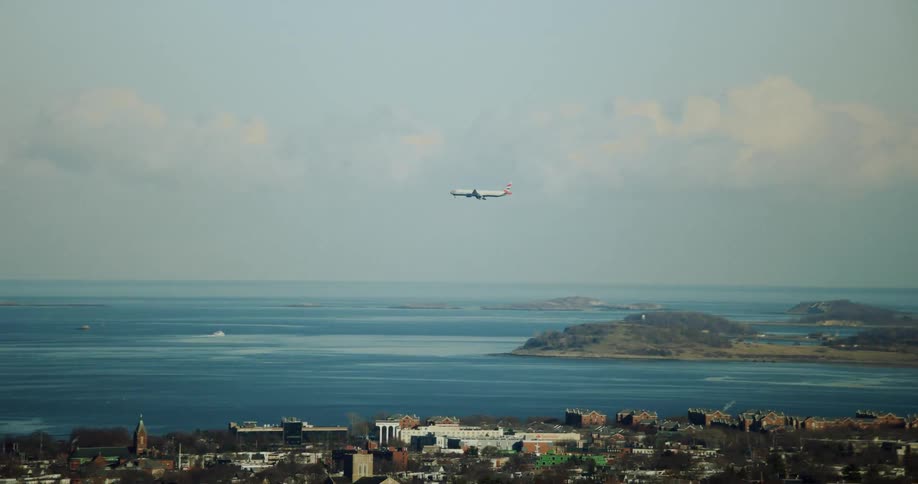 A breathtaking vista of a quaint seaside town offering a mesmerizing sight of an airplane gracefully gliding across the expansive sky enhancing the coastal allure