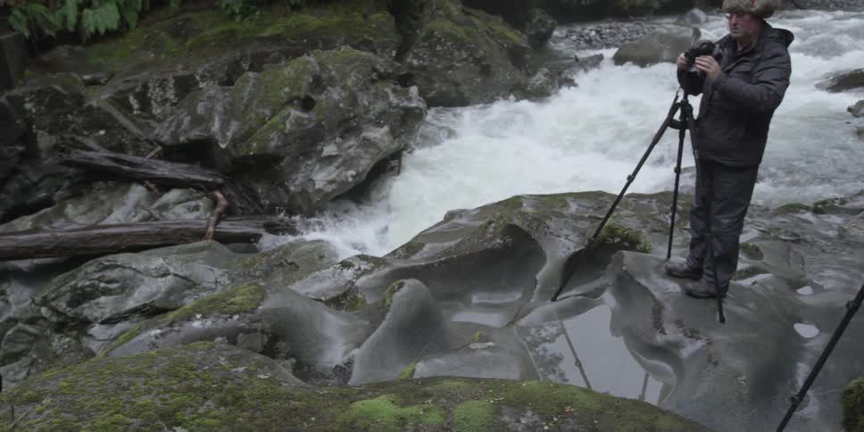 Two people are photographing a stream in front of them
