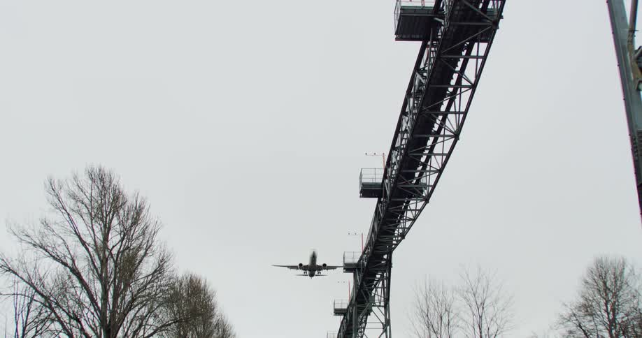 An airplane flies low over a trestle as it comes in for a landing