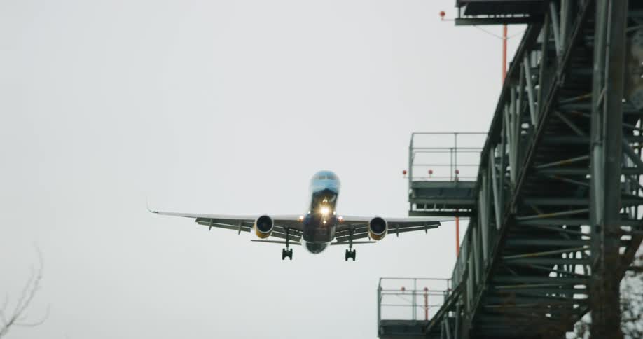 A large airplane descending above a steel structure
